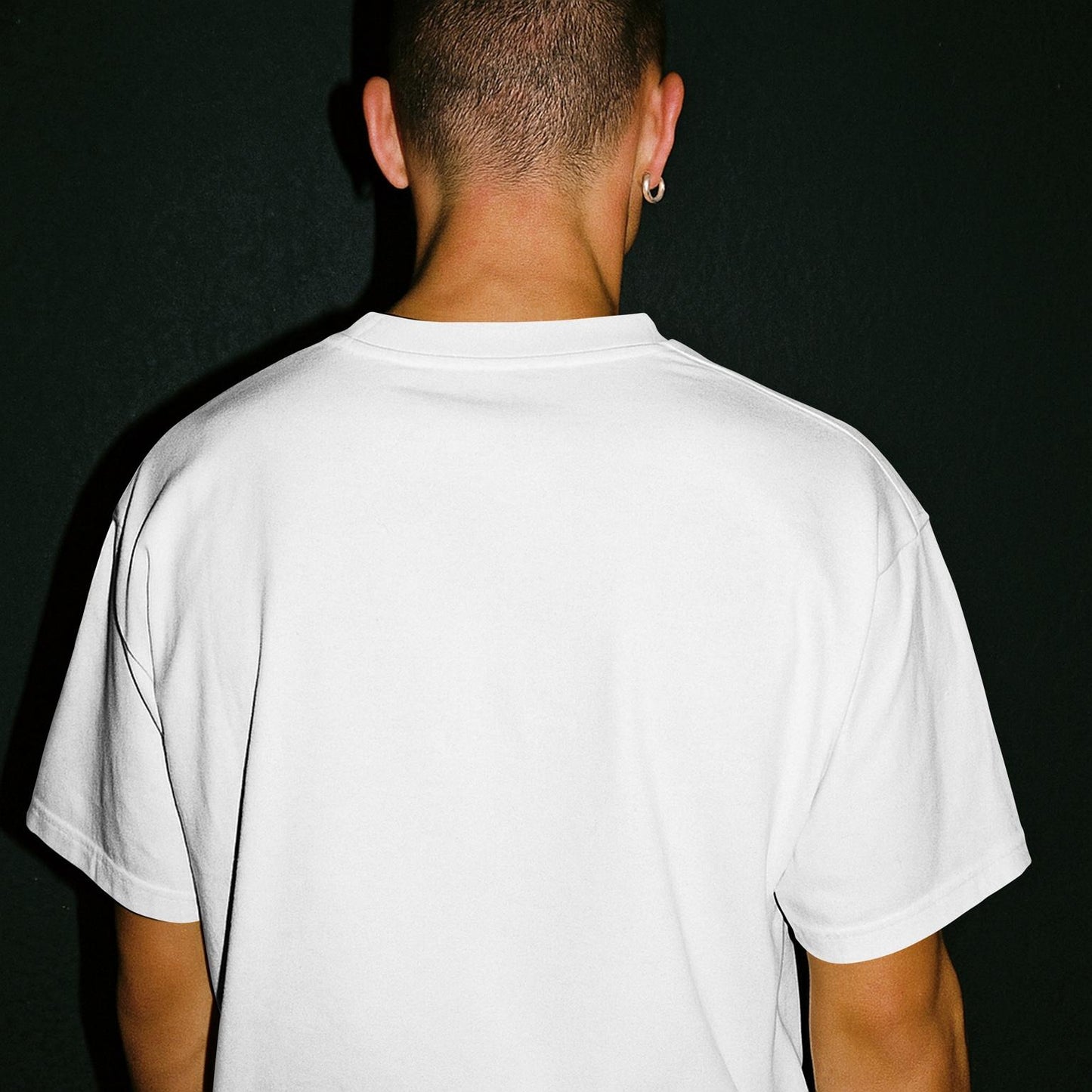 Vista trasera de camiseta blanca oversize sin estampado visible, fondo negro