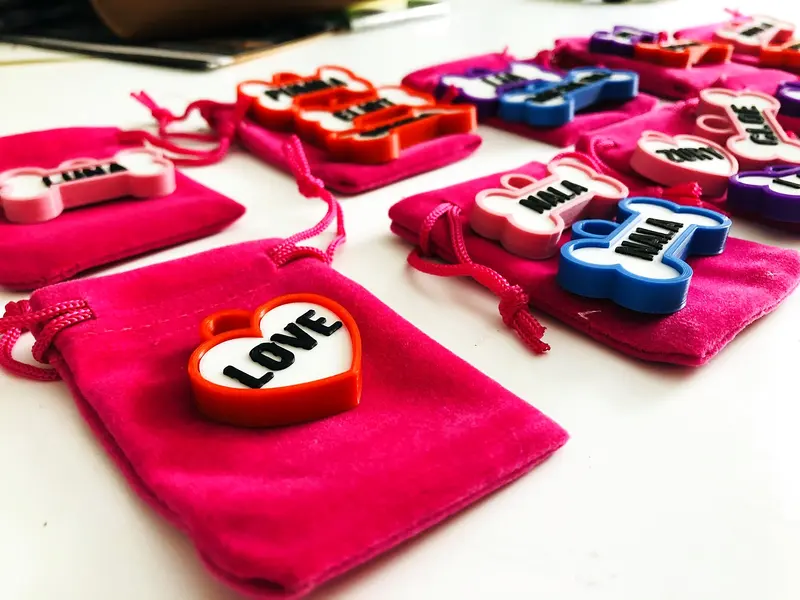 Chapitas de perro sobre bolsitas de terciopelo fucsia, con el corazón Love