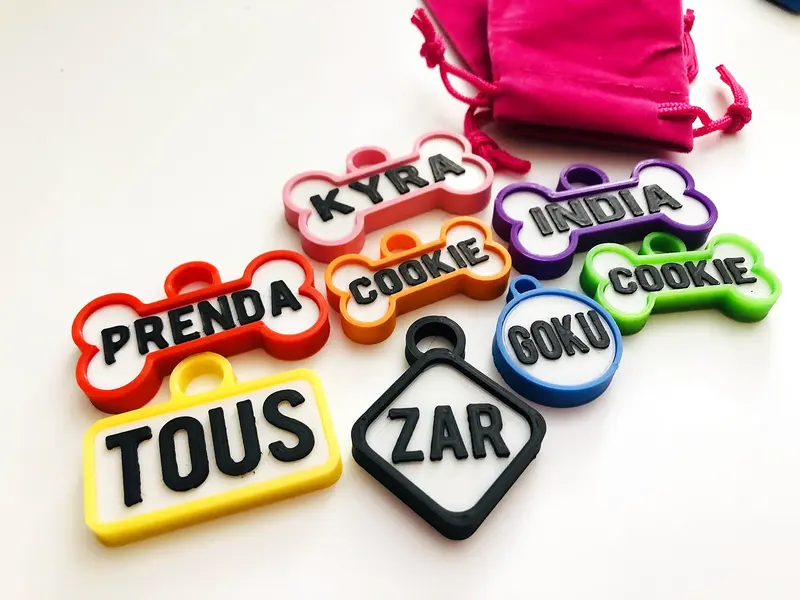 Chapitas de perro de varias formas con su bolsita: Kyra, Tous, Zar, Cookie, Prenda y Goku