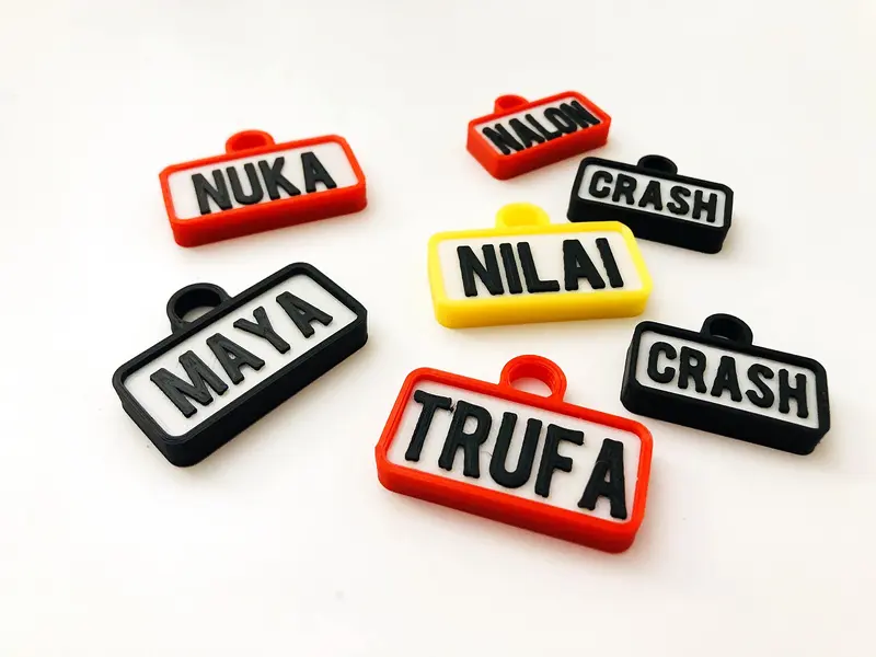 Chapitas de perro rectangulares negras, rojas y amarillas: Maya, Nilai, Trufa y Crash