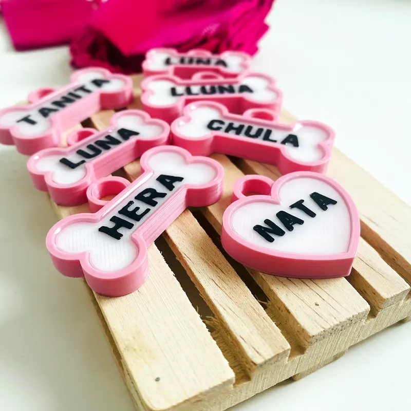 Chapitas de perro rosas sobre madera: Hera, Nata, Chula, Luna y Tanita